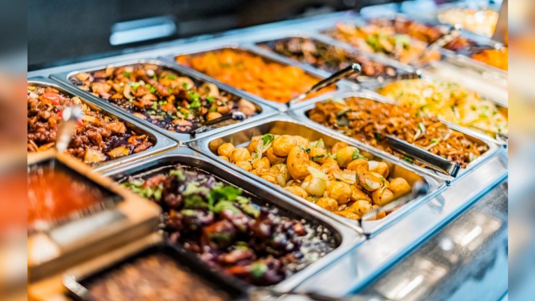 Variedade de pratos quentes e frios em uma estação de buffet, incluindo opções de legumes, carne, arroz e saladas, ideal para refeições em restaurantes ou eventos.