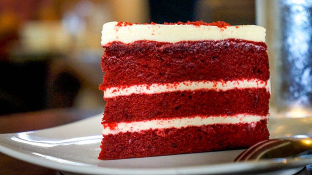 Fatia de bolo red velvet fit com camadas de creme, decorada de forma apetitosa em um prato branco, ideal para sobremesas e festas especiais.