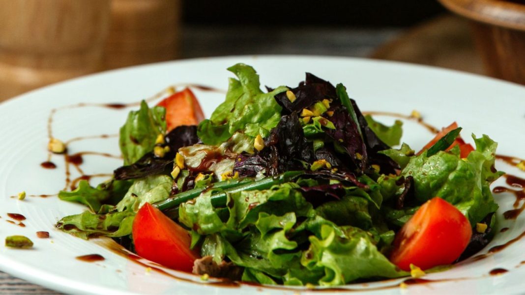Salada verde com tomates cereja e pitada de castanhas, servida com molho balsâmico, ideal para uma alimentação saudável.