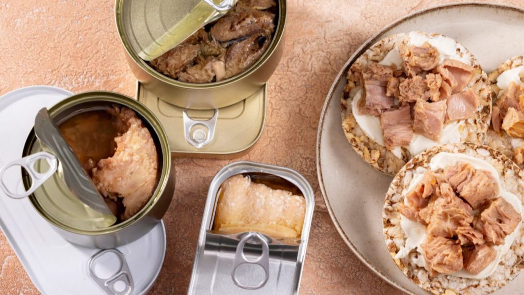 Diversas opções de comida enlatada e picada de atum apresentadas em uma mesa, incluindo saladas de atum e pedaços de atum enlatado.